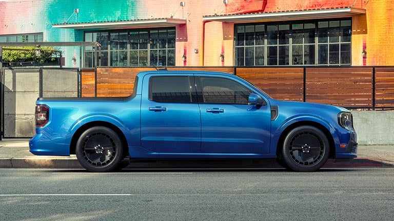 Profile view of a blue Ford Maverick® Lobo™ pickup parked in front of a restaurant patio